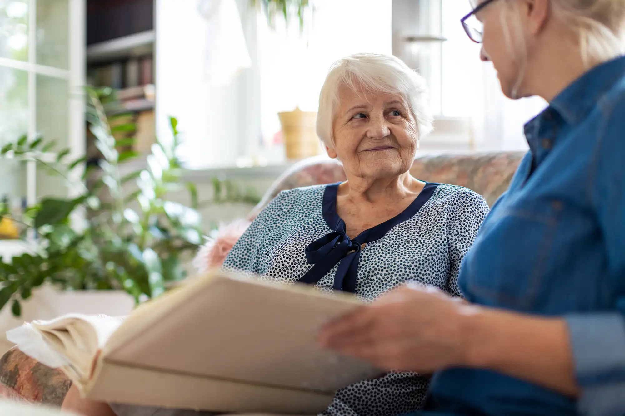 senior woman with adult woman looking at book